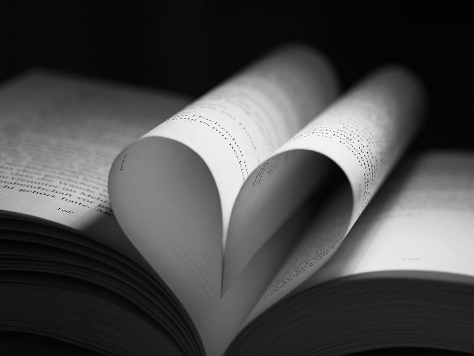 A small paper heart resting on a stack of handwritten pages